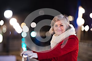 Senior woman on a walk in night city. Winter