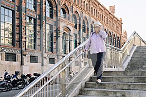 senior woman walking down stairs in the city