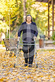 Senior woman walking outdoors with walker in autumn park