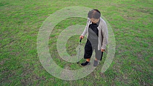 Senior woman walking with walking stick in the grass field