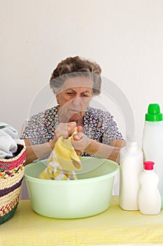 A senior woman is washing cloths by hand