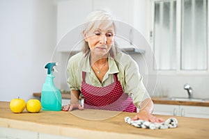 Senior woman washing kitchen table during cleanup