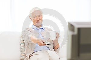 Senior woman watching tv and drinking tea at home