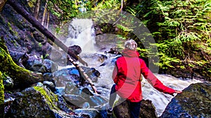 Senior woman watching the Waterfall on Mcgillivray Creek between the towns of Whitecroft and Sun Peaks