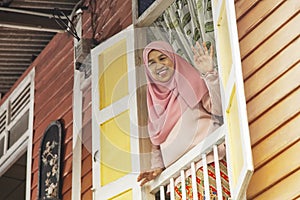 Senior woman waving from house window