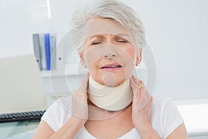 Senior woman wearing cervical collar in medical office