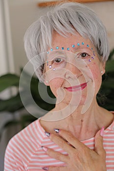 Senior woman wearing extravagant gemstones on face make up