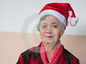 Senior woman wearing a Santa Claus hat and looking at the camera. Concept of aged people and Christmas and new year festival
