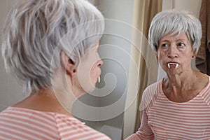 Senior woman wearing spooky vampire fangs