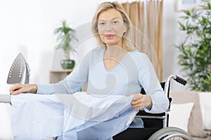 Senior woman in wheelcahir ironing clothes