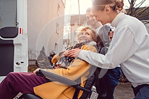 Senior woman in wheelchair being picked up by transport service photo