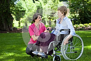 Senior woman on wheelchair with caring caregiver photo