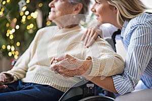 A senior woman in wheelchair with a health visitor at home at Christmas time.