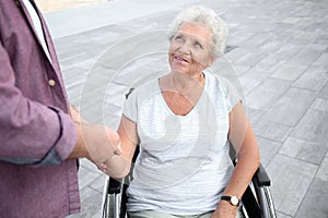 Senior woman in wheelchair and her husband outdoors