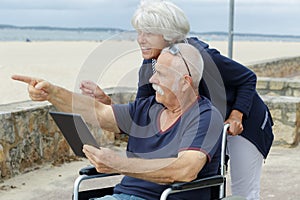 senior woman and wheelchair husband on beach