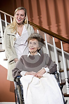 Senior woman in wheelchair with nurse helping