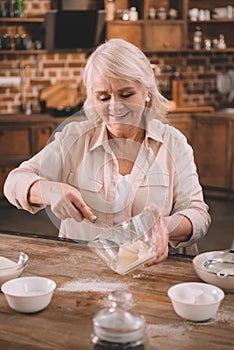 Senior woman whipping cream with whisk in glass bowl