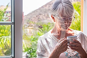 Senior woman at the window holding a coffee cup