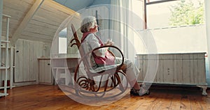 Senior woman, window and relax with tea in home for vision, memory and thinking in rocking chair. Elderly person, coffee