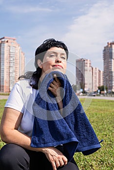 Senior woman wiping out sweat after hard workout outdoors in the park