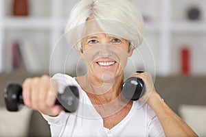 senior woman working out with dumbbells in home