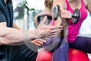 Senior woman working out with dumbbells with personal trainer
