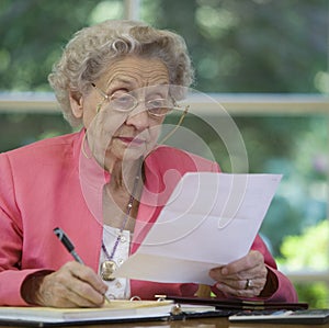 Senior woman writing a check paying bill