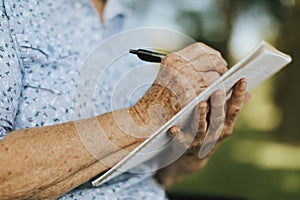 Senior woman writing down her memories into a notebook