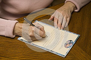Senior woman writing a letter with pen and paper photo