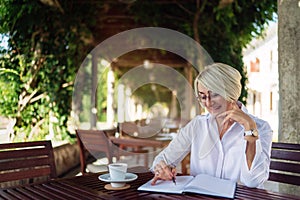 Senior woman writing to notebook or diary at a cafe