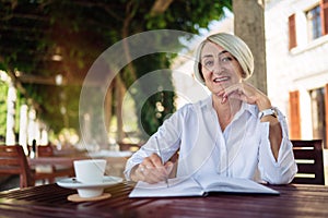 Senior woman writing to notebook or diary at a cafe