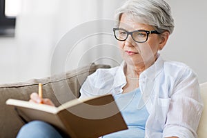 Senior woman writing to notebook or diary at home