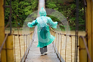 Senior woman 60 years old Crossing River by hinged bridge in forest