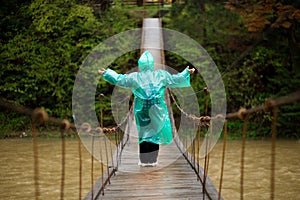Senior woman 60 years old Crossing River by hinged bridge in forest