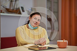 Senior woman in yellow sweater looking in the camera with mask