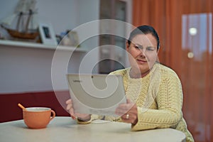 Senior woman in yellow sweater looking laptop with unhappy face
