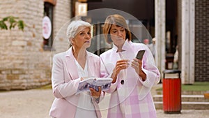 Senior women with city guide and smartphone