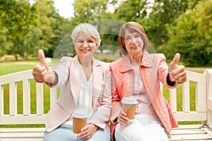 Senior women with coffee showing thumbs up at park
