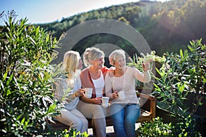 Senior women friends sitting outdoors on terrace, resting.