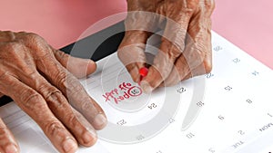 senior women hand putting push mark on pay debt word on calendar