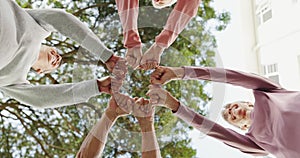 Senior, women and hands together with unity for support with low angle, happy or circle fist in nature. Elderly, group