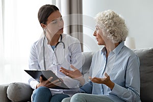 Senior woman telling about health complaints to young nurse photo