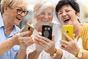 Senior women using mobile phones together