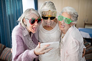 Senior women wearing novelty glasses making face while taking selfie photo