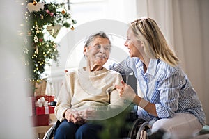 A senior woman in wheelchair with a health visitor at home at Christmas time.