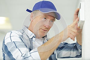 senior worker adjusting electronic thermostat