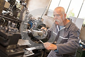 Senior worker doing shift at metalworks factory photo