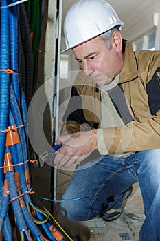Senior worker twisting tie around bundle cable trunking