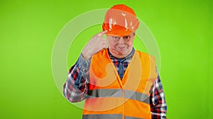 Senior worker in uniform hit helmet with hammer to check quality of hard hat.
