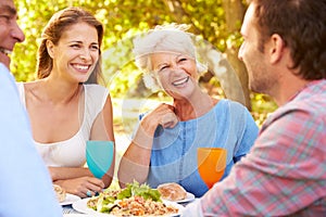 A senior and a young adult couple eating together outdoors